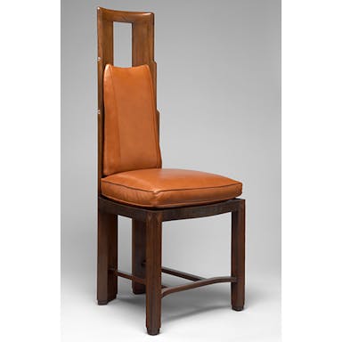 Photograph of brown wood and leather chair against grey background