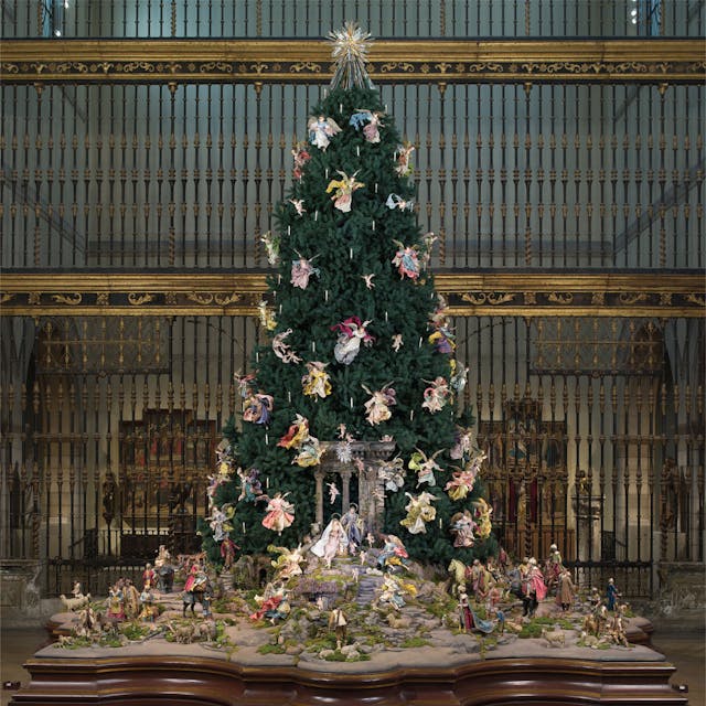 A Christmas tree decorated with Neapolitan crèche figures in front of the eighteenth-century Spanish choir screen from the Cathedral of Valladolid in the Museum's Medieval Sculpture Hall.