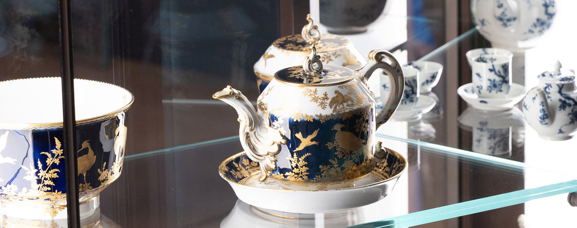 A blue-and-gold teapot in a glass display case.