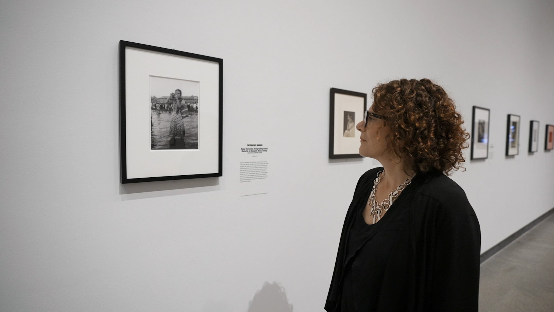 A woman looks at photographs hung in a gallery